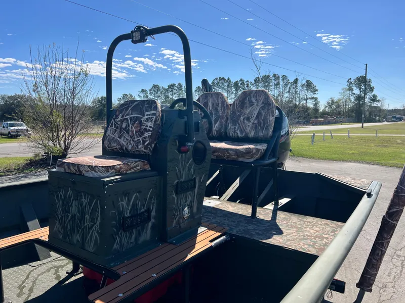 Slide: The Image of 2012 SeaArk 1872 boat with camo seats and console, parked outdoors under clear sky. - 12