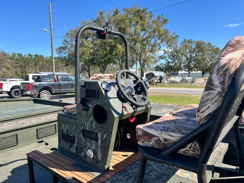 Slide: The Image of 2012 SeaArk 1872 boat with camo seats and steering console, parked outdoors. - 13