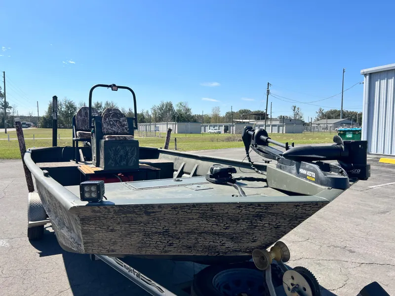 Slide: The Image of 2012 SeaArk 1872 boat with camouflage design, parked outdoors under clear blue sky. - 17