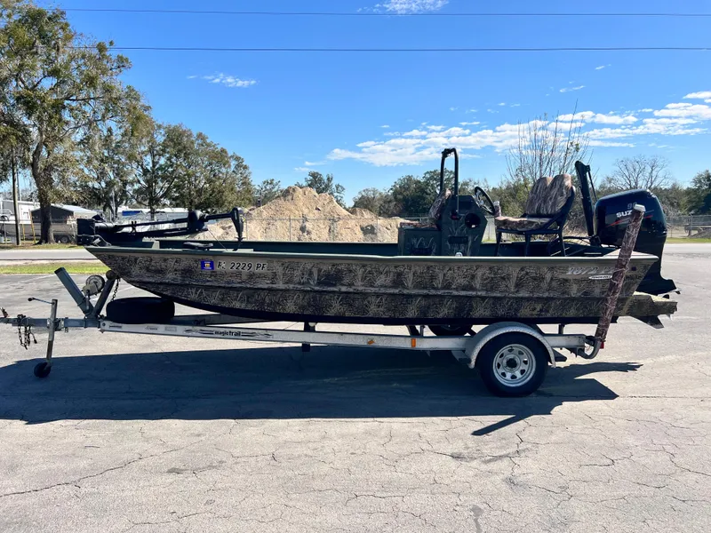 Slide: The Image of 2012 SeaArk 1872 boat on trailer, parked outdoors under clear sky. - 2