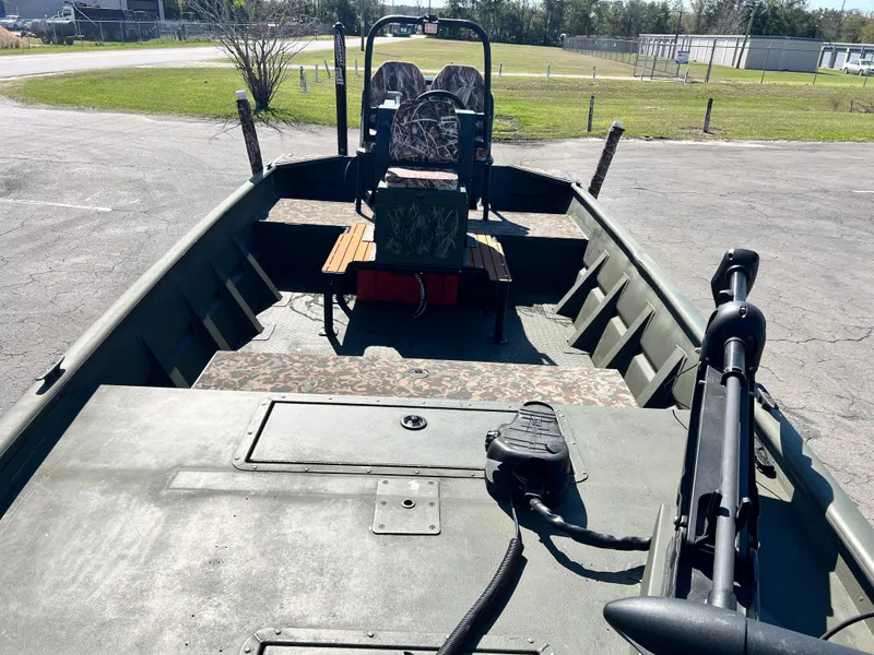 Slide: The Image of 2012 SeaArk 1872 boat interior with camo seats and trolling motor, parked outdoors. - 21