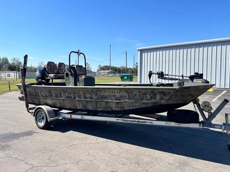 Slide: The Image of 2012 SeaArk 1872 boat on trailer, parked outdoors under clear blue sky. - 4