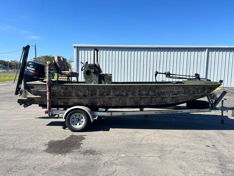 Slide: The Image of 2012 SeaArk 1872 boat on trailer, camo design, parked outdoors. - 5