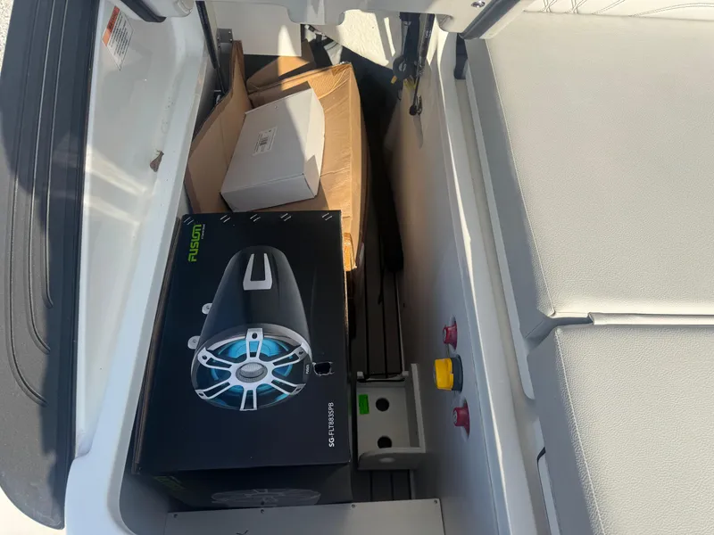 Slide: The Image of Storage compartment of 2025 Sea Ray SLX 260 with Fusion speaker box and other items. - 23