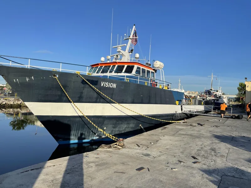 Slide: The Image of Custom Offshore Supply Vessel 2002 docked at a harbor, named "Vision," under clear blue skies. - 2
