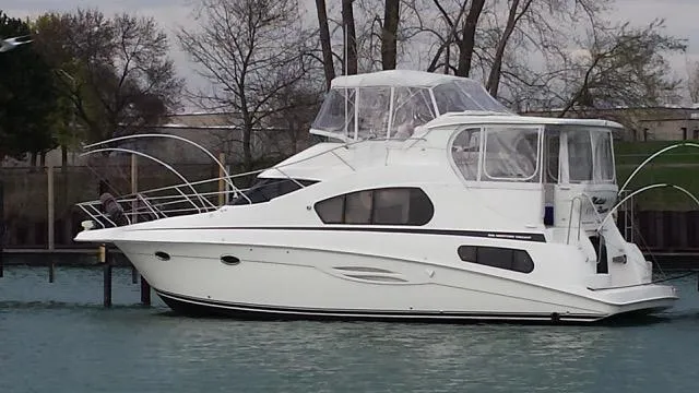 Slide: The Image of 2003 Silverton 39 Motor Yacht docked on calm water, surrounded by trees. - 2
