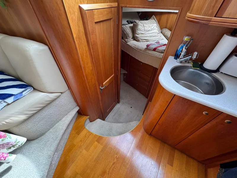Slide: The Image of 2003 Silverton 39 Motor Yacht interior with wood finish, kitchenette, and cozy sleeping area. - 25