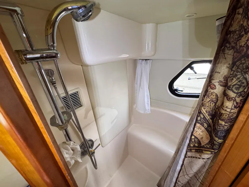 Slide: The Image of 2003 Silverton 39 Motor Yacht bathroom with shower, window, and patterned curtain. - 33