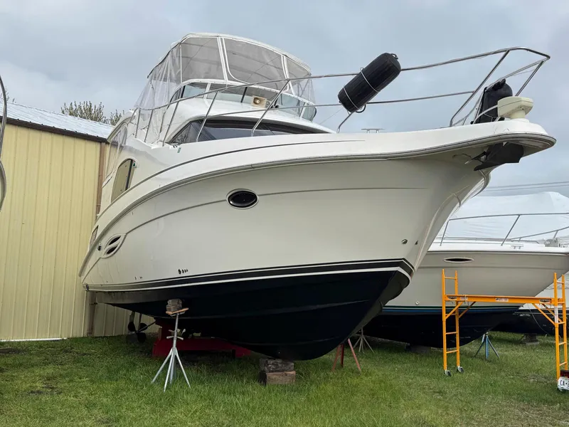 Slide: The Image of 2003 Silverton 39 Motor Yacht on dry dock, white exterior, covered cockpit, near yellow building. - 8