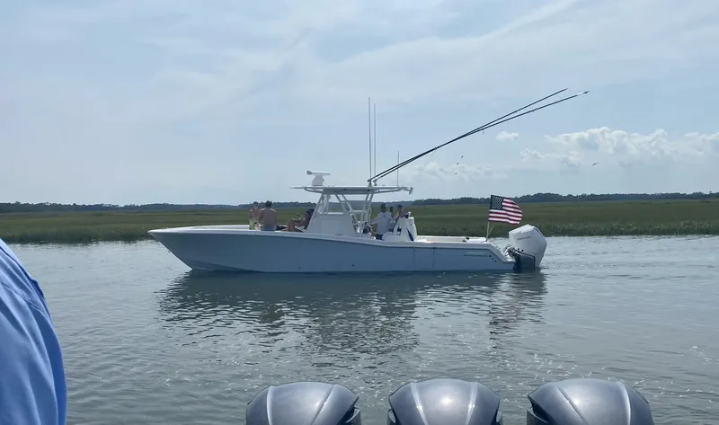 Slide: The Image of 2021 Invincible 36 Open Fisherman boat on calm water, American flag, clear sky. - 2