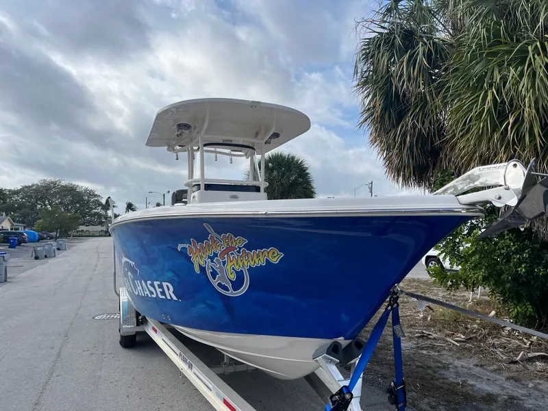 Slide: The Image of 2025 Sea Chaser 30 HFC CC boat on trailer, blue hull, parked near palm trees. - 13