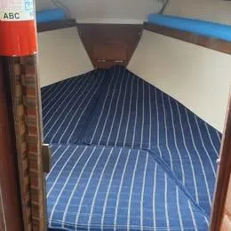 Slide: The Image of Interior cabin of a 1984 Catalina Sloop with striped blue cushions. - 12