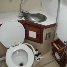 Slide: The Image of 1984 Catalina Sloop bathroom with toilet, sink, and wooden cabinetry. - 15