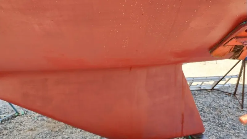 Slide: The Image of 1984 Catalina Sloop keel in dry dock, showing red hull and rudder. - 5