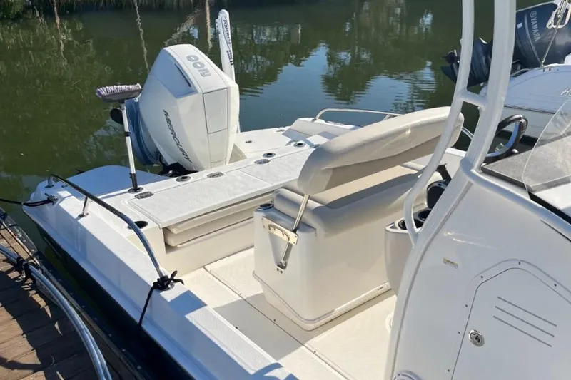 Slide: The Image of 2019 Boston Whaler 210 Dauntless boat with seating and outboard motor, docked by water. - 2