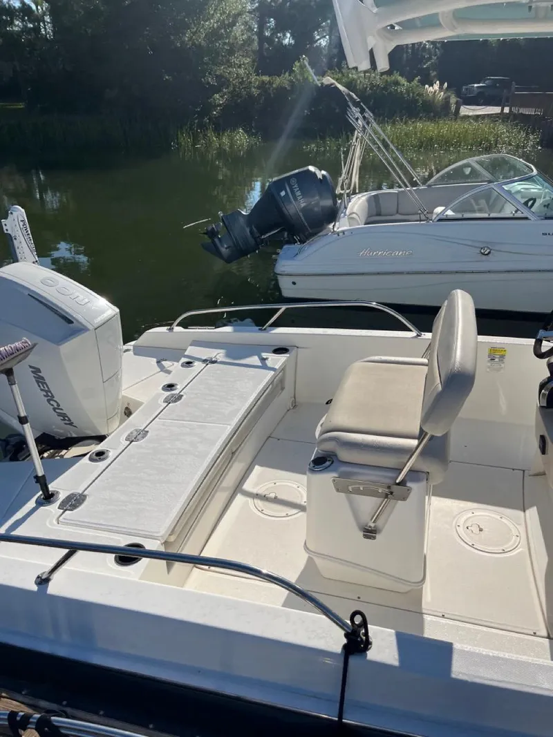Slide: The Image of 2019 Boston Whaler 210 Dauntless boat interior with seating and motor, docked on calm water. - 3