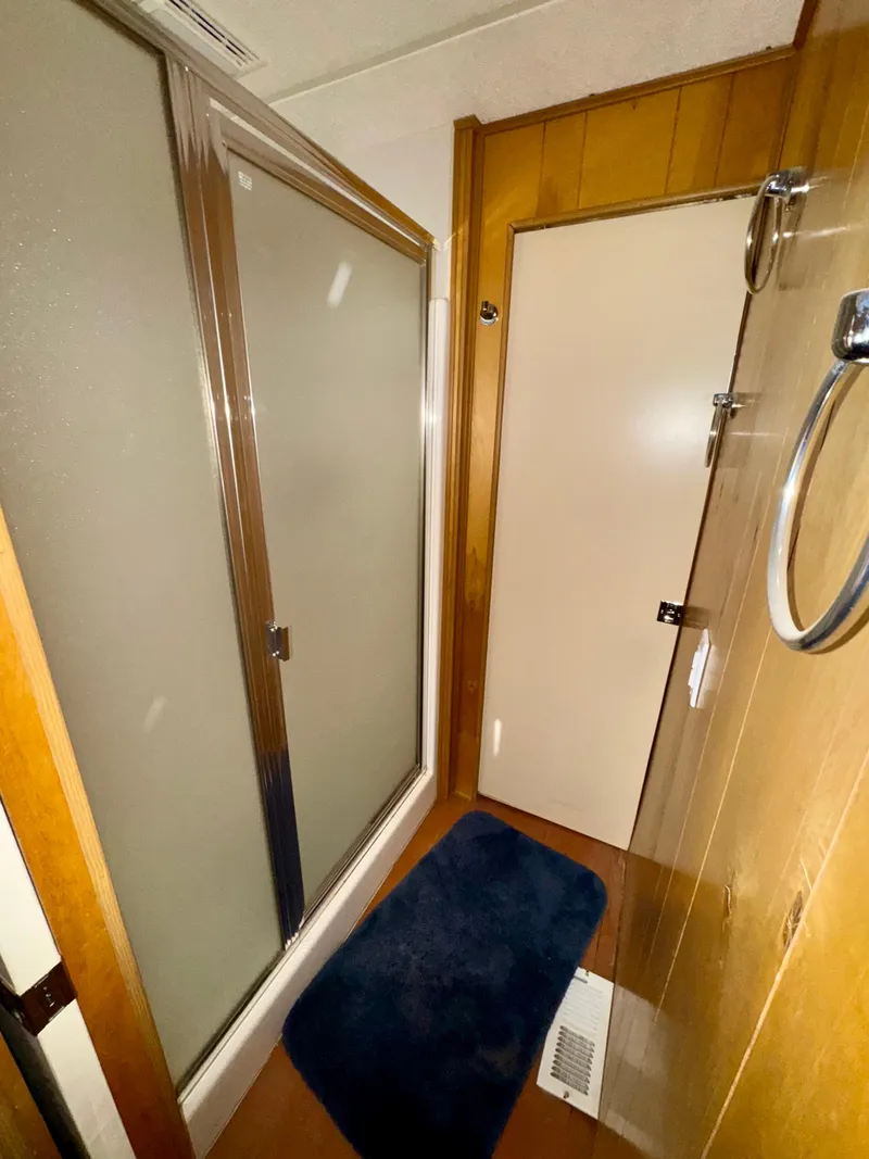 Slide: The Image of Compact bathroom with shower, wooden paneling, and blue rug in 1993 Lakeview model. - 10