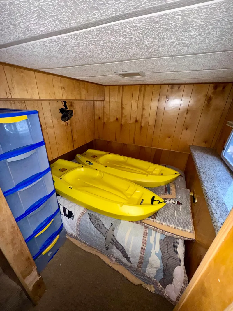 Slide: The Image of Small wooden room with yellow kayaks on a bed, blue storage drawers, and a window. - 13