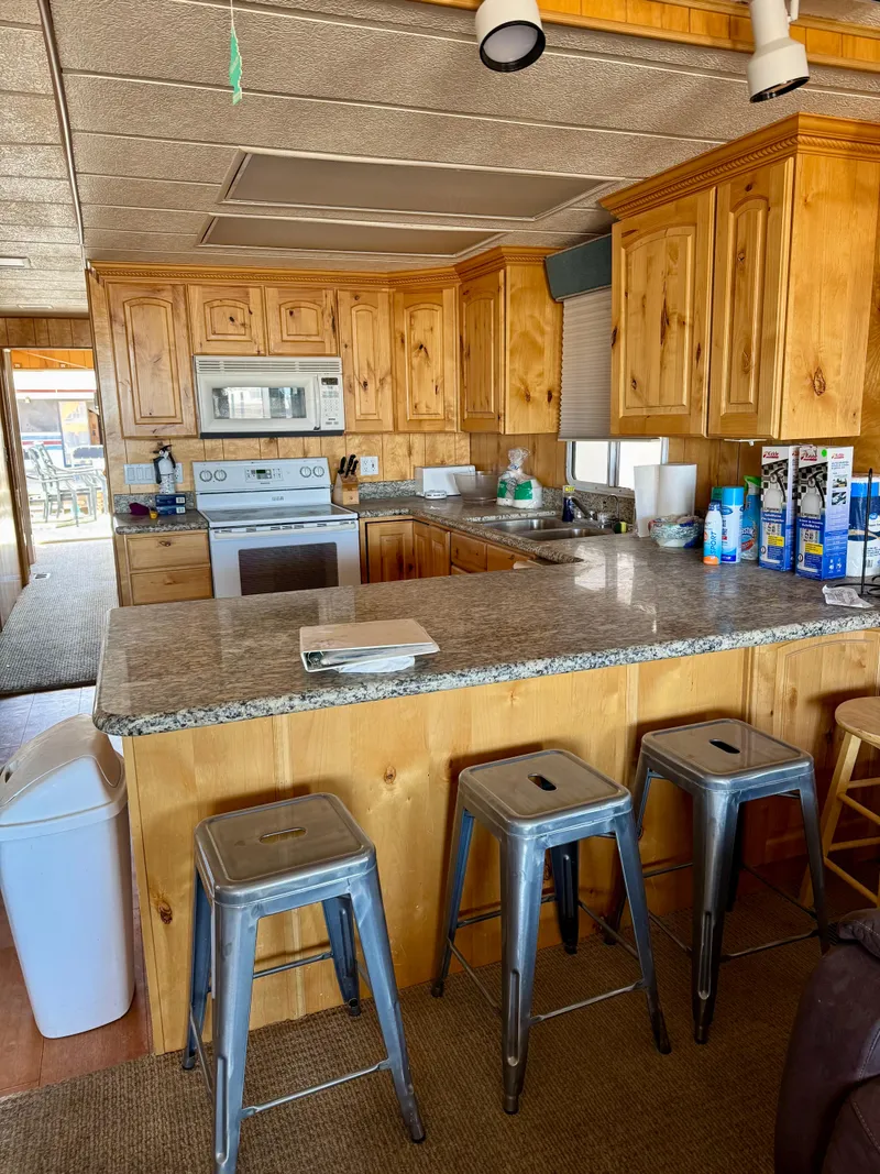 Slide: The Image of Rustic kitchen with wooden cabinets, granite countertops, and metal stools in a 1993 Lakeview model. - 4