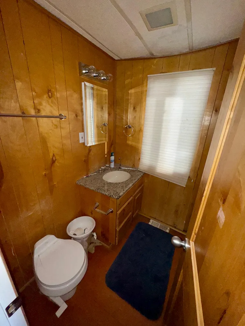 Slide: The Image of Wood-paneled bathroom with granite countertop, toilet, and window. Lakeview Full Ownership, 1993 model. - 7