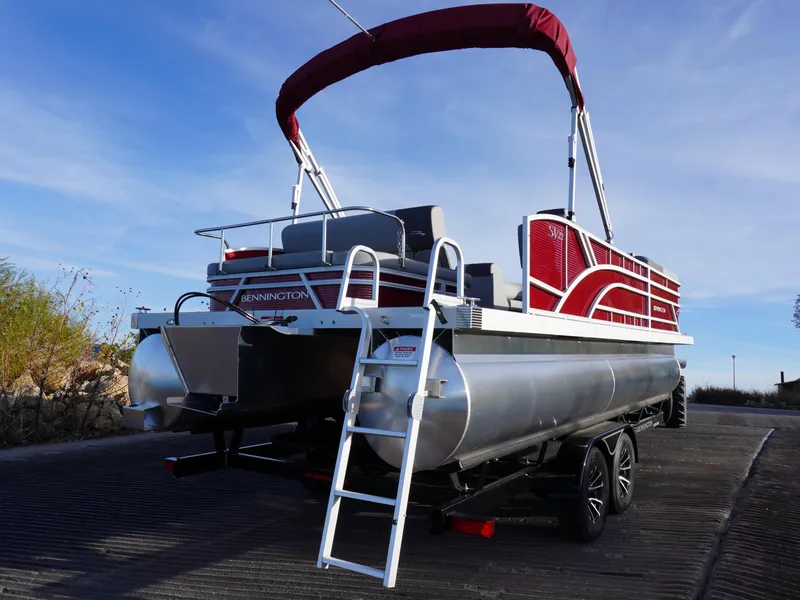 Slide: The Image of 2025 Bennington 22 SVSB pontoon boat with red canopy on trailer. - 3
