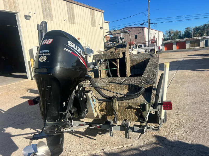 Slide: The Image of 2015 Gator Trax 18 boat with Suzuki 90 engine parked outside a building. - 2