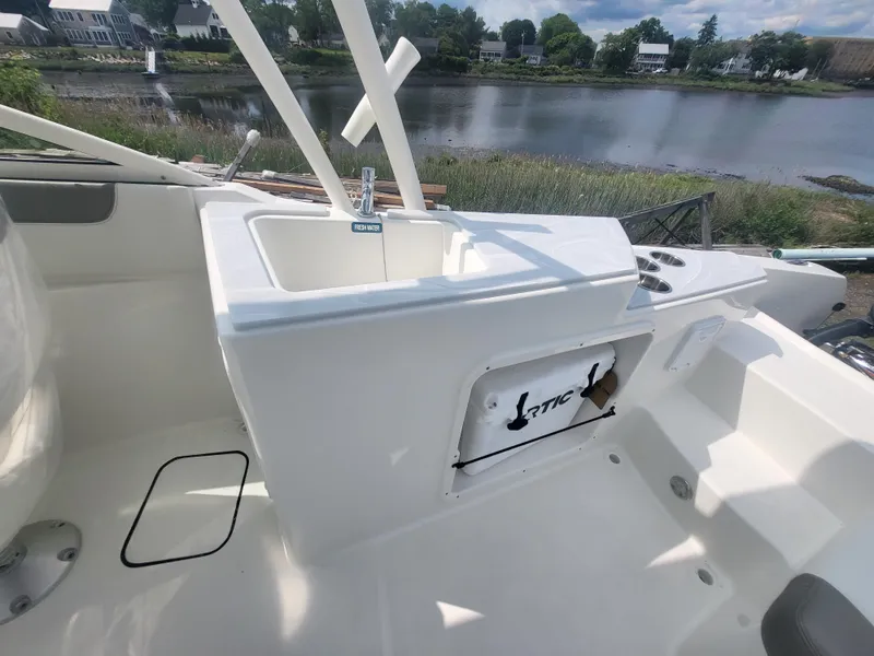 Slide: The Image of 2024 World Cat 230 SD boat interior with sink and storage, overlooking a scenic river. - 7