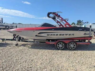 Slide: The Image of 2014 Malibu Wakesetter 22 MXZ boat on trailer, red and white design, parked on gravel. - 8
