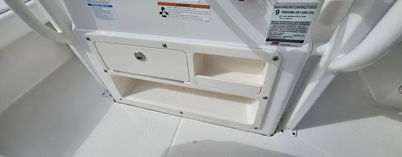 Slide: The Image of 2018 Robalo 246 Cayman boat storage compartment with safety labels. - 12
