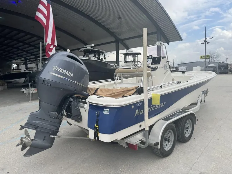 Slide: The Image of 2019 NauticStar 215 XTS boat with Yamaha motor on trailer, parked under a canopy. - 11