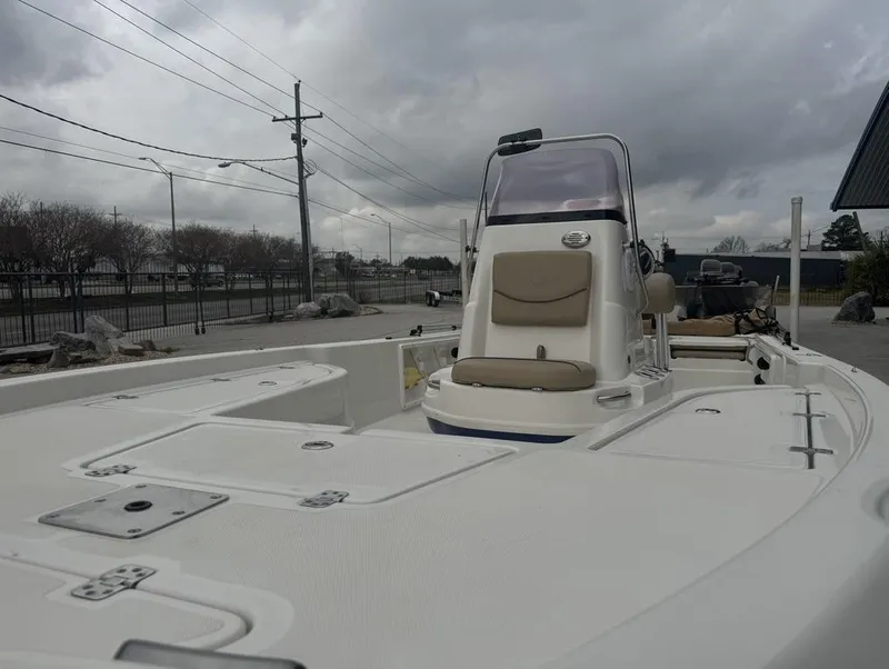 Slide: The Image of 2019 NauticStar 215 XTS boat with center console, parked outdoors under cloudy skies. - 13
