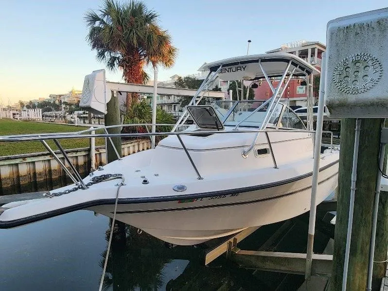 Slide: The Image of 2003 Century 2300V boat docked near palm trees and waterfront homes. - 2