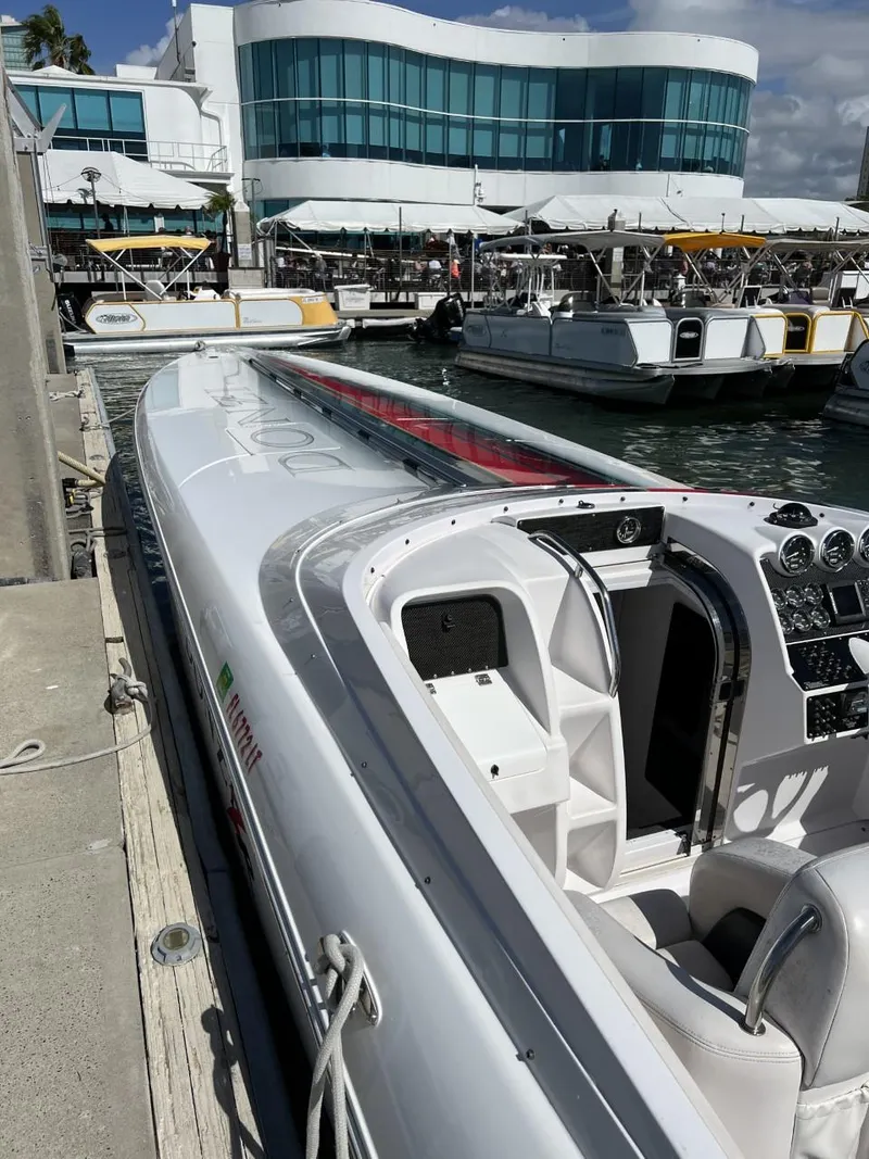 Slide: The Image of 2008 Donzi 43 ZR speedboat docked at marina, modern building in background. - 17