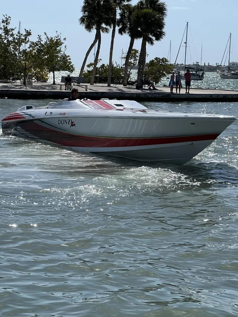 Slide: The Image of 2008 Donzi 43 ZR speedboat cruising near a tropical shoreline with palm trees. - 2