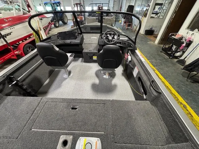 Slide: The Image of 2025 Crestliner 1650 Hawk boat interior with dual seats and steering console in showroom. - 20