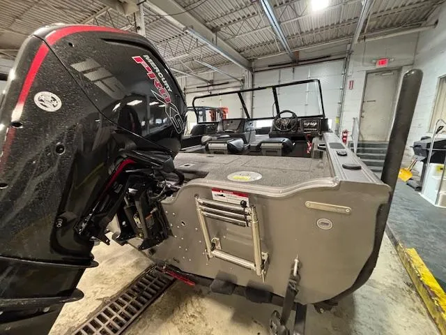 Slide: The Image of 2025 Crestliner 1750 Fish Hawk boat in a garage, featuring a powerful outboard motor. - 23