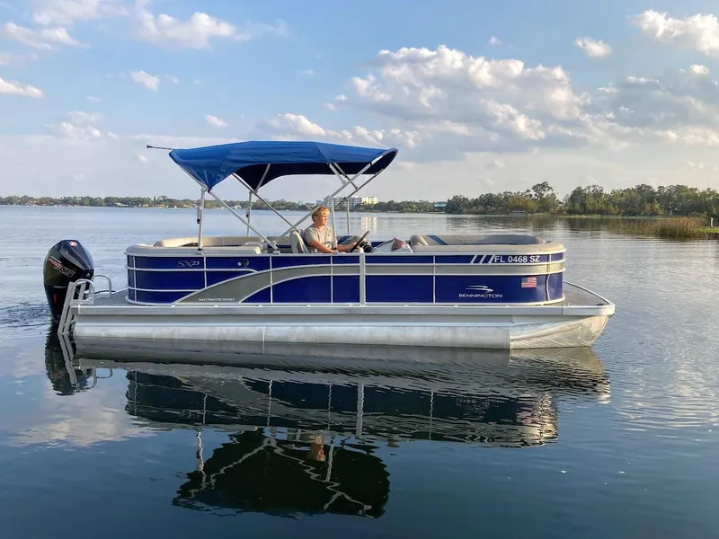 Slide: The Image of 2021 Bennington SX23 pontoon boat with 175HP Mercury engine on a calm lake. - 3