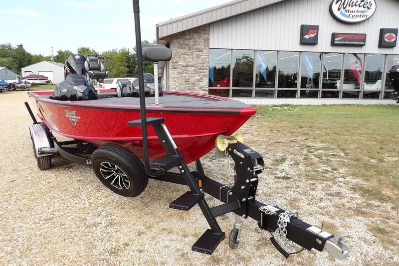 Slide: The Image of 2025 Lund 2075 Pro-V Bass XS boat in red, parked outside a marine center. - 56