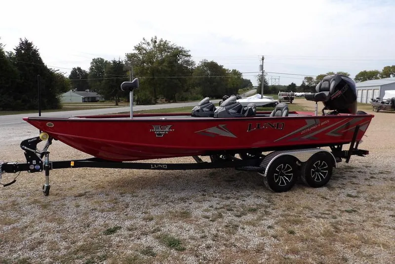 Slide: The Image of 2025 Lund 2075 Pro-V Bass XS boat on trailer, red exterior, parked outdoors. - 8