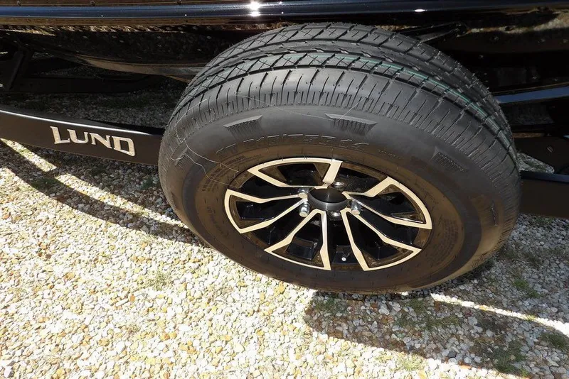 Slide: The Image of 2025 Lund 2075 Pro-V Bass XS trailer wheel on gravel surface. - 50