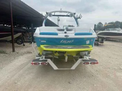 Slide: The Image of 2024 Tigé Z3 boat, vibrant blue and yellow, parked on gravel near other boats. - 4
