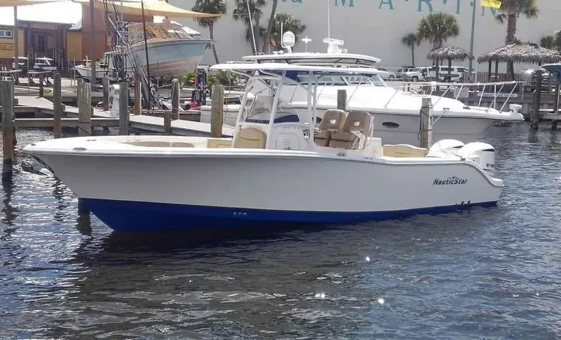 Slide: The Image of 2019 NauticStar 28 XS Offshore boat docked in marina, featuring sleek design and dual engines. - 0