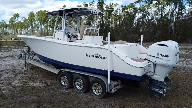 Slide: The Image of 2019 NauticStar 28 XS Offshore boat on trailer with Yamaha engine, parked outdoors. - 13
