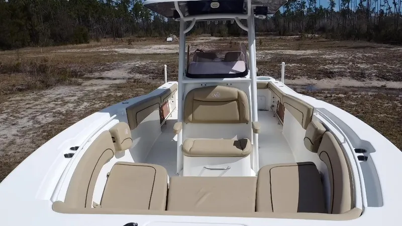 Slide: The Image of 2019 NauticStar 28 XS Offshore boat interior with beige seating, set in a natural landscape. - 22