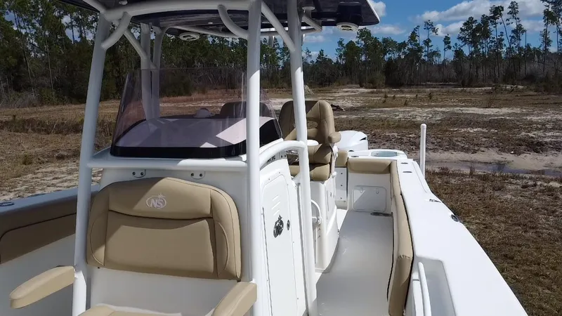 Slide: The Image of 2019 NauticStar 28 XS Offshore boat with beige seating, parked on a grassy area. - 24