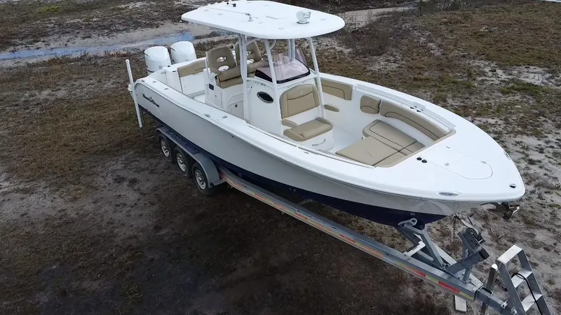 Slide: The Image of 2019 NauticStar 28 XS Offshore boat on trailer, parked on grassy terrain. - 9