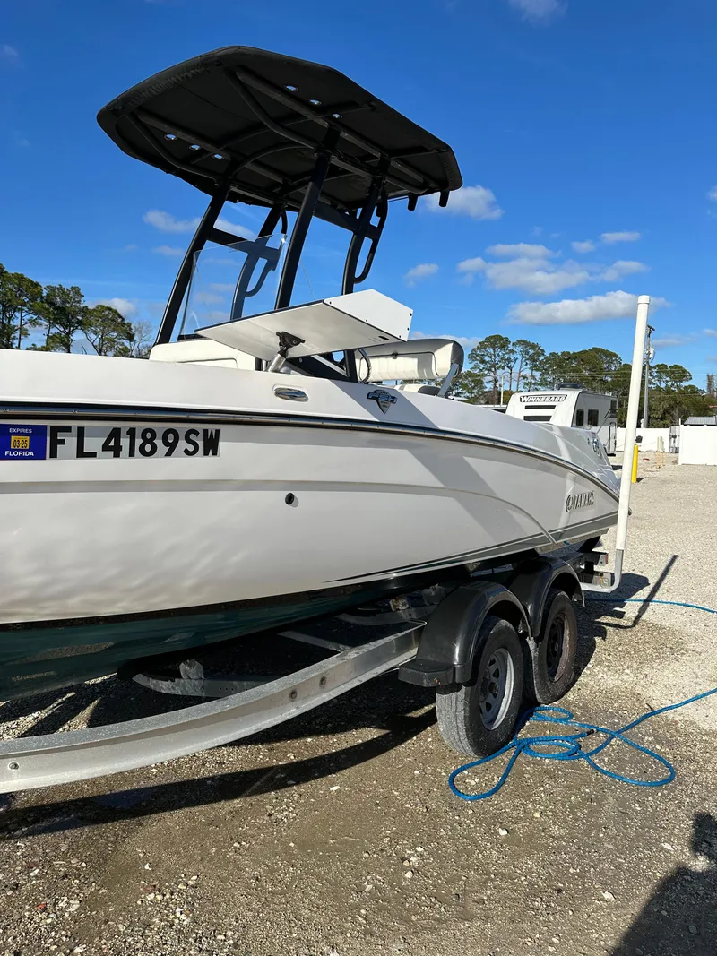 Slide: The Image of 2021 Yamaha Boats 210 FSH Sport on trailer, parked outdoors under clear blue sky. - 26