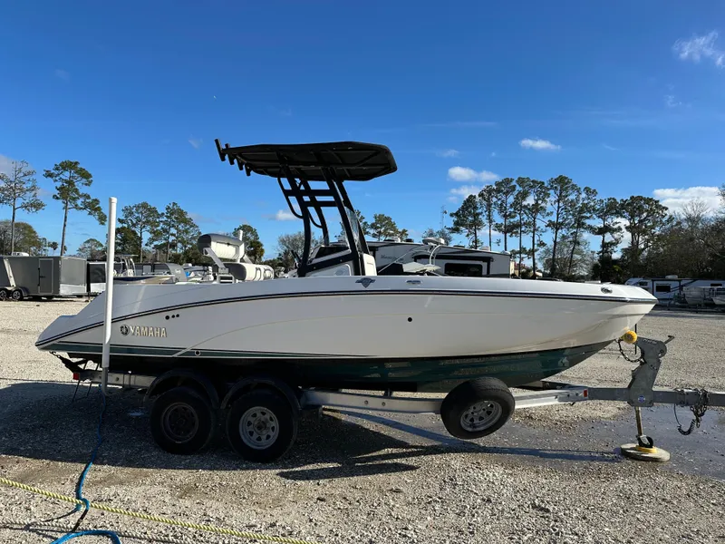 Slide: The Image of 2021 Yamaha Boats 210 FSH Sport on trailer, parked outdoors under clear blue sky. - 3