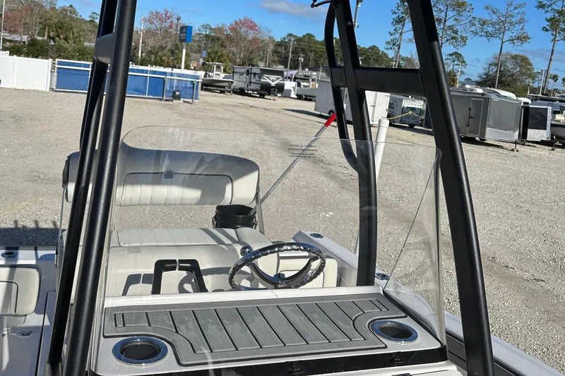 Slide: The Image of 2021 Yamaha Boats 210 FSH Sport interior with steering wheel and seating, parked outdoors. - 45