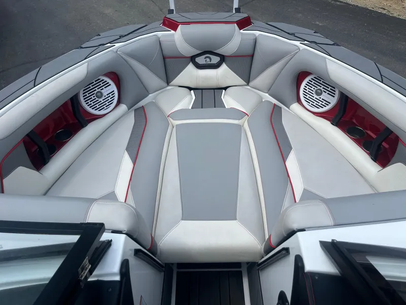 Slide: The Image of 2022 Centurion Ri230 boat interior with gray and red seating, featuring built-in speakers. - 20